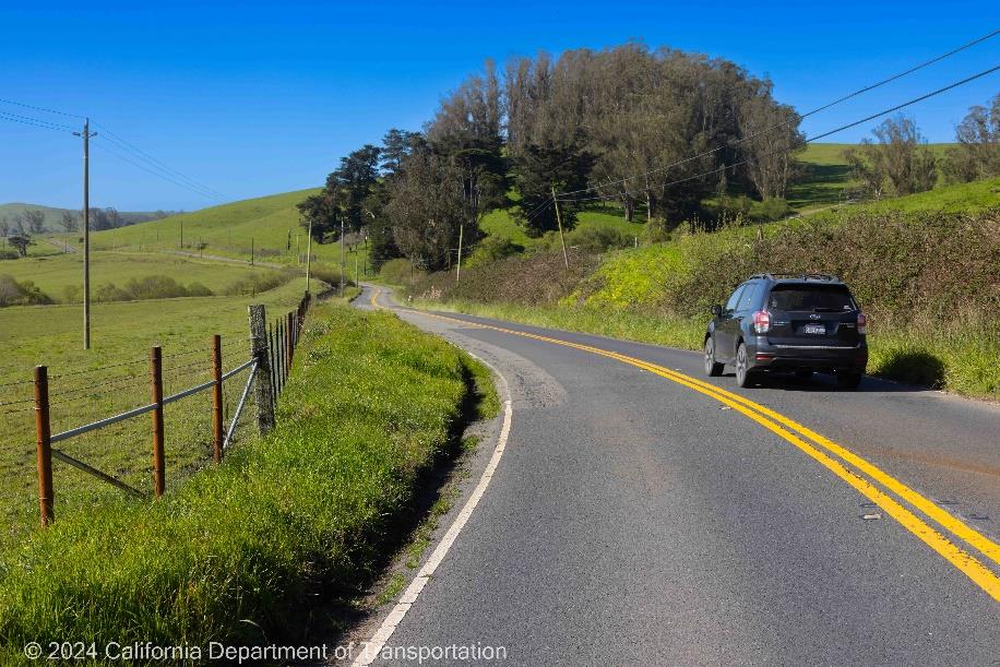 Car drives on two lane section of State Route 1 in Marin County.