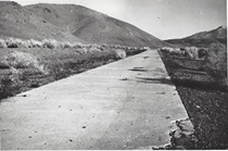 A black and white picture of an eight foot wide slab of concrete pavement south of Big Pine in 1910.