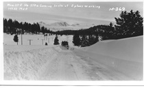 A black and white image for a snowplow pushing snow off the road near Crestview in 1952. A second plow is unseen behind the first one. Writing on the picture reads 'Mono County, 23, East State Route 270 Looking South at 2 plows working. 1-17-52, M.E.F. M-369."