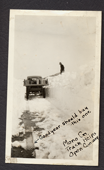 An undated black and white image showing a truck driving through snow with snowbanks nearly as tall as the truck. Writing on the image reads "Good Year should by this one (with an arrow pointing to tire tread). Mono County Truck Helps Open Conway."