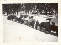 An undated black and white image showing a group of men surrounded by snow removal vehicles and snow.