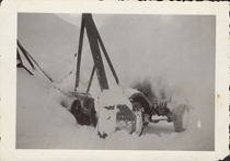An undated black and white image of a snowblower removing snow from the highway. The vehicle is masked behind a cloud of snow.