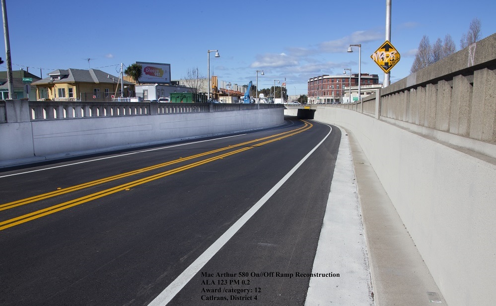 A newly paved two lane highway with historic-looking cement barriers on either side of the road.