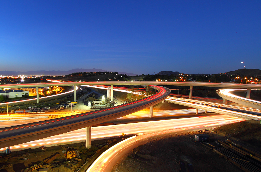 A view of several freeways curving and interweaving with cars driving by in a blurred motion.