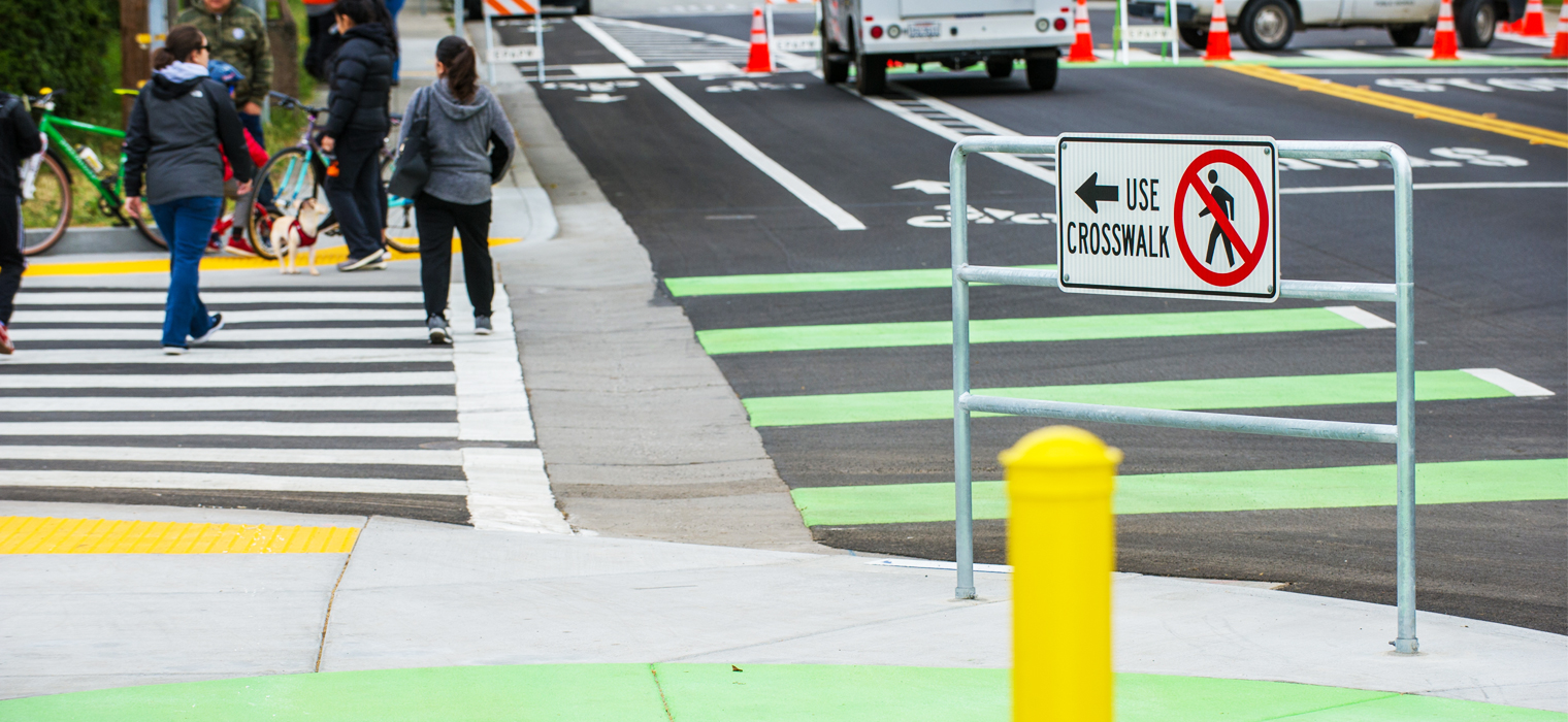 Photo of pedestrians on new crosswalk on Clark Street in E. Palo Alto. New safety features include green striping and signs.