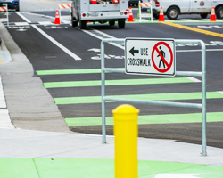 Photo thumbnail of a new pedestrian crosswalk featuring rails, signs, and road striping.