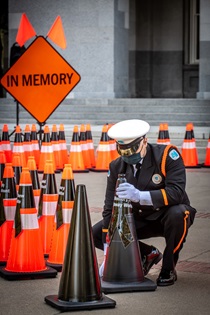 Caltrans Honor Guard member honors all fallen highway workers with the placement of a black cone; an orange "In Memory" sign is visible in the background - 31st Annual Caltrans Workers Memorial Ceremony April 29, 2021 - California State Capitol, Sacramento