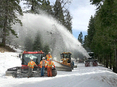 The Caltrans Long Barn Sierra Pass Crew, (left to right and front to back) Erik Young, Tim McGrath, Jim Longeway, and Steve Belit pose with the new PistenBully snow cat, while Serge Kiriluk is operating the blower.