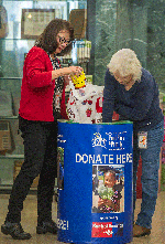 From left to right, Caltrans Resource Analyst Dinah Lee and California Public Records Act Coordinator Marcy Freer put food donations in a Sacramento Food Bank barrel at Headquarters.