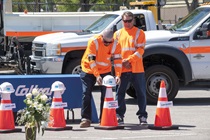 Inyokern maintenance worker Peyton Smith lays a Caltrans helmet on a traffic cone in honor of District 9’s fallen workers as Robert Sonnenberg looks on  (Photo by Michael Lingberg)