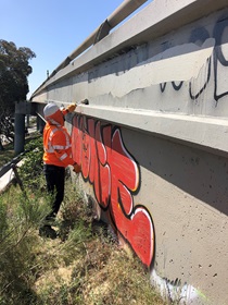 District 11’s Bryan Barraza covers graffiti along southbound Interstate 5 at the B Street ramp in downtown San Diego.