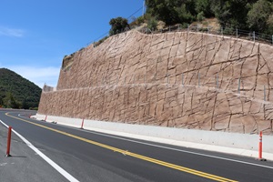 Large retaining wall stands over a two-lane highway.