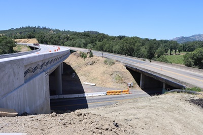The new Calpella Bridge is visible alongside the old Calpella bridge under a blue sky with a county road running underneath. 