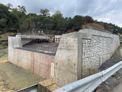 Construction of Eel River Bridge Replacement in Mendocino County. A new abutment for the bridge is visible without a bridge deck. 