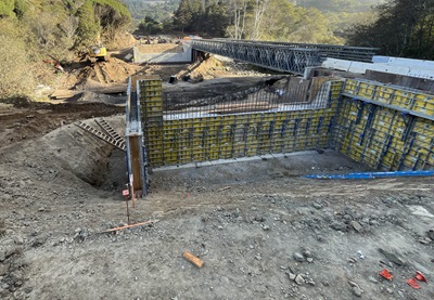 Installation of the concrete box girders at Elk Creek Bridge. A temporary metal bridge is erected in the background.