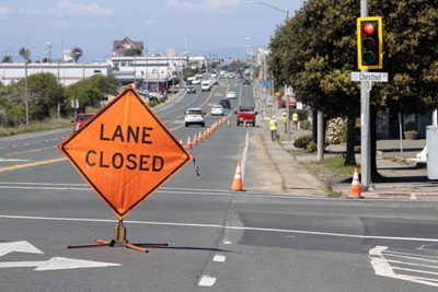 A sign reading Lane Closed stands in the road, announcing a lane closure on Route 1 in downtown Fort Bragg. 