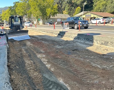 Heavy equipment grades a demolished lane of US 101 in Hopland as one-lane traffic continues to flow next to the work area.
