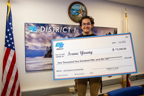 2023 scholarship recipient Isaac Young holds an oversized novelty check with his printed name in the amount of $2,250