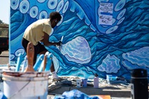 Artist's assistant Malachi Arthur paints a giant octopus at samoa bridges.