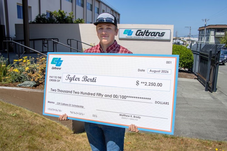 Person wearing a hat holding a giant check written out to Tyler Berti in the amount of $2,250.