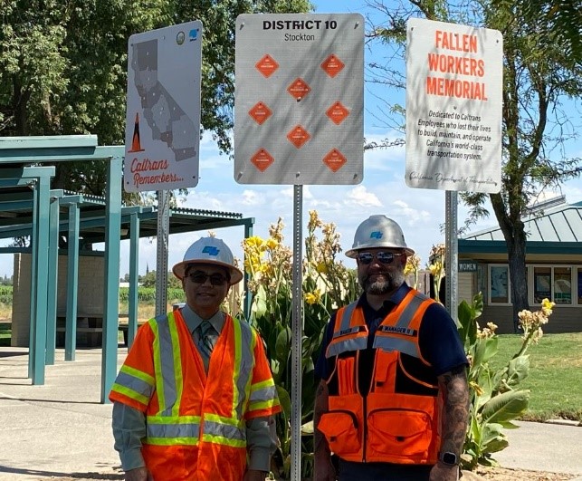 District 10 Director Dennis T. Agar (left) and Maintenance Manager Christopher Baker stand beneath the newly installed Fallen Workers Memorial sign at the Enoch Christofferson Rest Area near Turlock.
