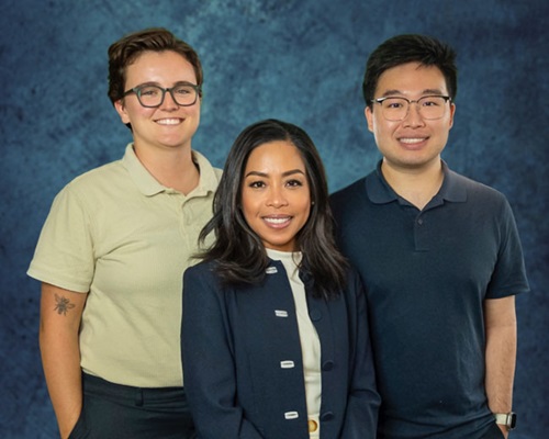 Picture of a group of three people in front of a blue background.