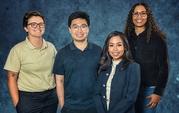 Group of four people in front of a blue background.