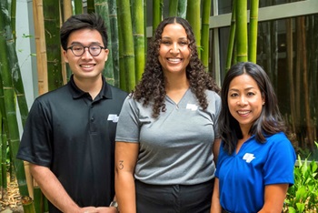 Three people in front of a blue background.