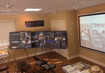 The presentation room with exhibit posters and showing a PowerPoint presentation. For more information, call (619) 688-6670 or email CT.Public.Information.D11@dot.ca.gov