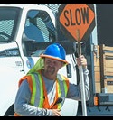 Caltrans work holding a slow sign next to truck