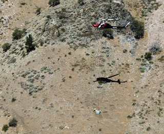 A helicopter delivers supplies along the westbound mountain slope of Interstate 80 for a rockfall protection project near the California-Nevada border. 