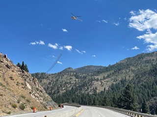 Wire mesh drapery is suspended from a helicopter along the mountain slope of Interstate 80 for a rockfall protection project near the California-Nevada border.