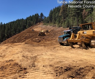Photo showing major excavation and road realignment work on State Route 20 in Nevada County. Heavy equipment preps a segment of slope for fill work in order to realign roadway curves. 