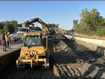 Crews rolling fresh asphalt along highway 49 in Placer County as part of a safety barrier project.