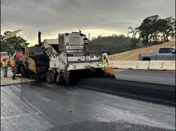 Crews rolling fresh asphalt along highway 49 in Placer County as part of a safety barrier project.