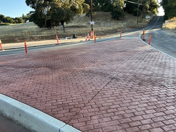 Newly constructed curb and concrete splitter island along State Route 49 as part of a safety barrier and roundabout project.