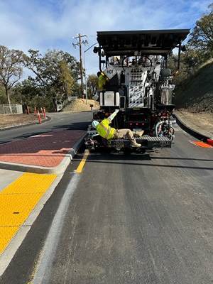 Crews placing final striping along State Route 49 as part of a roundabout and safety barrier project.