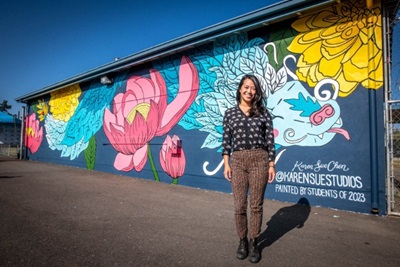 image of woman standing behind the mural artwork