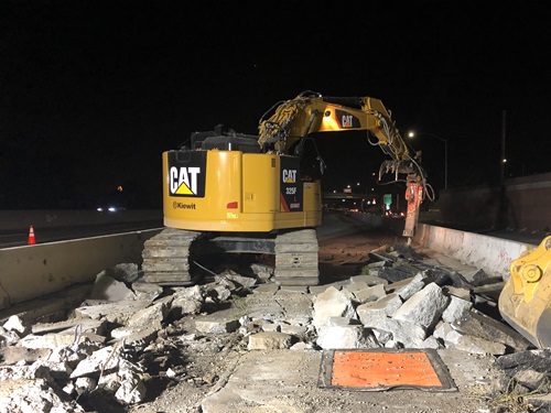 Construction crews demolishing concrete to create a new section of roadway
