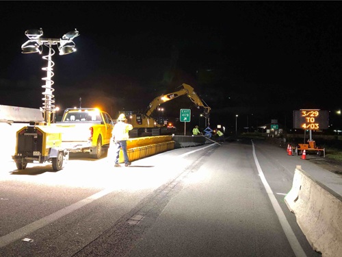 Construction crews preparing to install a variable toll message sign (VTMS) over the freeway lanes