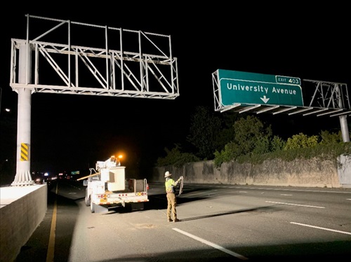 Construction crews working in the freeway lanes to install a new overhead sign