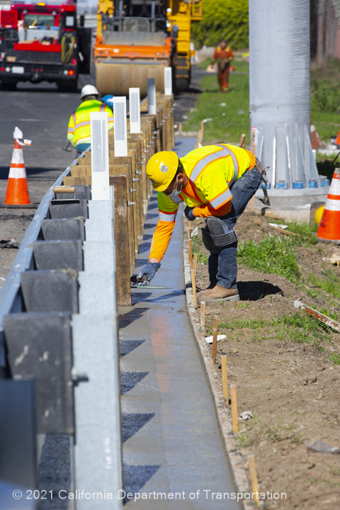Construction crew member installing new guardrail in the freeway shoulder