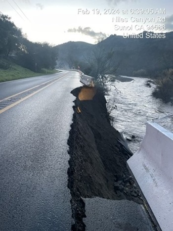 Photograph of State Route 84 near Sunol where the shoulder of the road has slipped out down an embankment towards a creek running alongside the roadway.