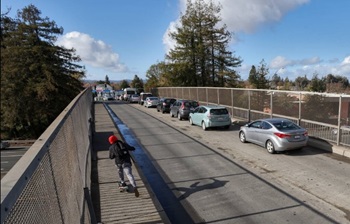 Photograph of the Hearn Avenue overcrossing of U.S. 101 in Santa Rosa, California. A bicyclist rides along the left-hand side of the roadway while cars are stopped on the right-hand side.