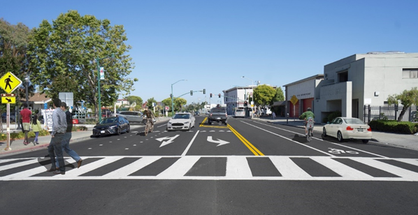 Rendering showing the Encinal Avenue with changes including upgraded curb ramps and enhanced crosswalk markings. This project also incorporates Complete Streets elements, which includes the conversion of the existing two through lanes to one through lane in each direction, a center two-way left-turn lane, two Class II bicycle lanes, and parking within the project limits.