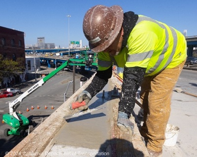 A person performs repairs on a concrete barrier during the San Francisco Barrier Repair Project on November 10th, 2024.