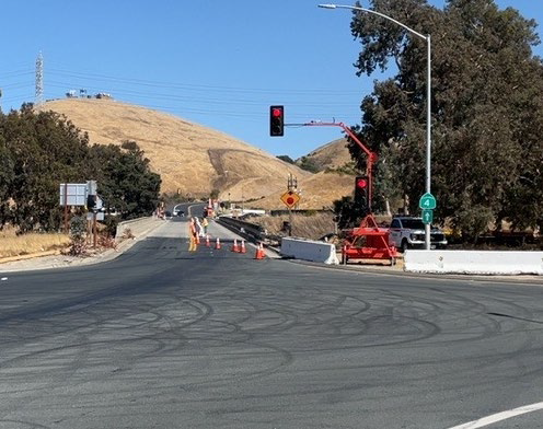 Photograph of the Cummings Skyway overcrossing above I-80 in Contra Costa County. One lane is blocked off with cones and temporary traffic signals have been placed to accommodate one-way traffic controls during guardrail replacement and concrete barrier installation.