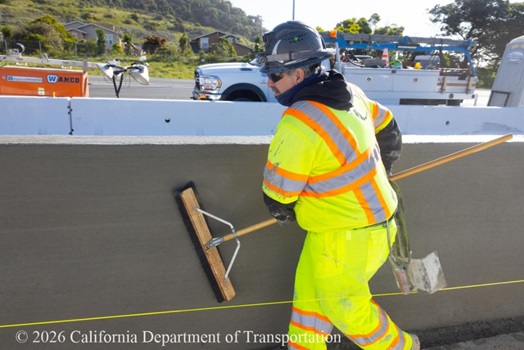 A Caltrans crewmember uses a broom to perform finishing work on the fresh concrete of a section of the new median on US 101 in San Francisco.