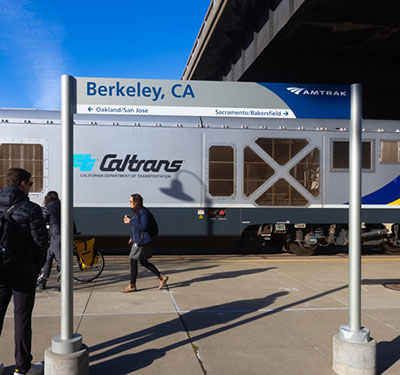 A photo of the Berkeley Amtrak Station with train and passengers walking by.