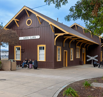 Santa Clara Amtrak Station with passengers sitting in front on a bench.